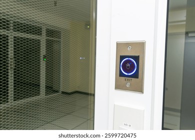 A close-up view of a modern exit button set against a sleek glass wall in a contemporary office space, emphasizing safety and accessibility in design.