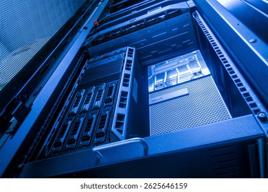 A close-up view of a modern server rack illuminated with blue lighting, showcasing advanced technology and intricate hardware setup for data storage and processing.