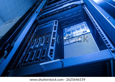 A close-up view of a modern server rack illuminated with blue lighting, showcasing advanced technology and intricate hardware setup for data storage and processing.