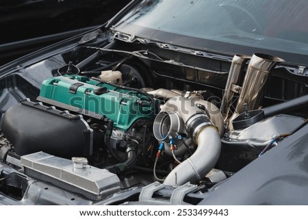 Close-up view of modified car engine, vibrant green valve cover, turbocharger, and intricate piping Ideal for automotive enthusiasts and performance vehicle projects