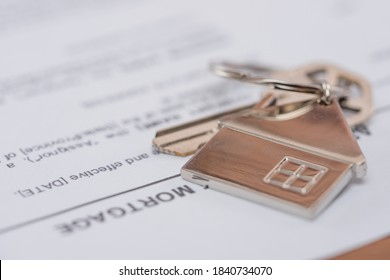 Close-up view of Mortgage loan agreement application with key and home shaped keychain. Signing agreement contract. New home concept. - Shutterstock ID 1840734070