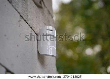Close-up view of a motion sensor mounted on an unfinished aerated concrete wall. Concept of home security, alarm system, and modern surveillance in construction stage.