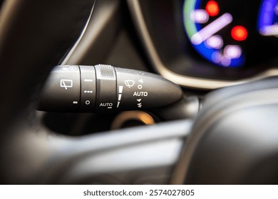 Close-up view of a multifunction wiper control lever inside a modern car, featuring automatic settings, windshield washer control, and advanced functionality for convenient driving.