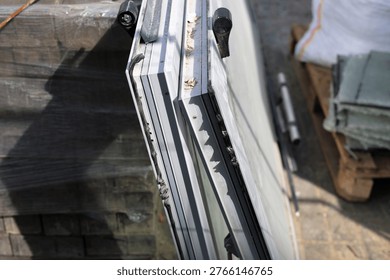 Close-up view of multiple double glazing glass units standing outdoors on a building site. New window panels ready for installation, showing black sealant layers and metal spacers for thermal insulation