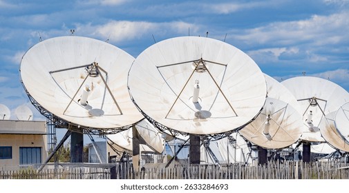 Close-up view of multiple large satellite dishes at a ground telecommunication station 