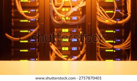 Close-up view of multiple server racks glowing with yellow and blue lights, interconnected by numerous orange network cables in a professional data center environment.