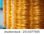 Close-up view of neatly wound copper wire coils in a manufacturing environment. The image highlights the vibrant metallic sheen of the copper against a blurred industrial background