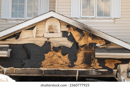 A close-up view of a neighborhood garage roof, which bears the scars of recent accidental fire damage, expertly extinguished by firefighters in the midst of a tranquil autumn.
