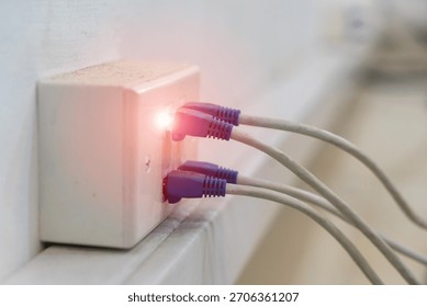 A close-up view of a network connection point featuring multiple Ethernet cables plugged in, with a glowing light indicator signaling active connectivity and data transfer.