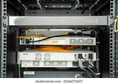 A close-up view of a network server rack featuring neatly organized hardware components, including switches, routers, and fiber optic cables. 