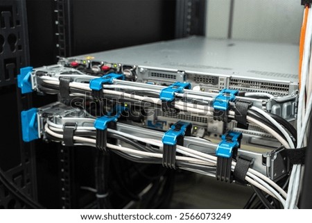 A close-up view of a network server rack featuring neatly organized hardware components, including switches, routers, and fiber optic cables. 