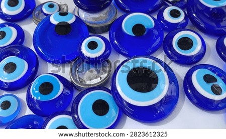 A close-up view of numerous blue evil eye charms, showcasing their intricate designs and vibrant color, symbolizing protection against bad luck.