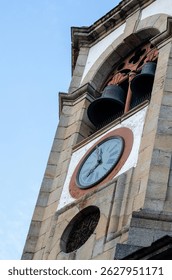Close-up view of an old clock tower with bells on a clear day. Perfect for illustrating European cityscapes, historic buildings, and travel backgrounds.