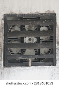Close-up view of an old grimy wall exhaust fan covered with dust and dirt behind plastic slats