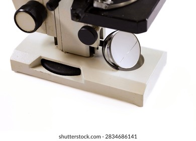 Close-up view of an old laboratory microscope showing the lenses, stage, focusing knobs and mirror.