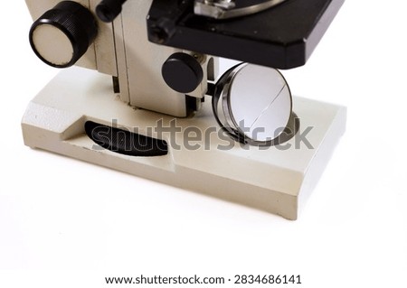 Close-up view of an old laboratory microscope showing the lenses, stage, focusing knobs and mirror.