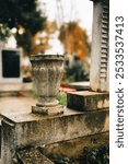 A close-up view of an old stone urn in a cemetery with blurred background