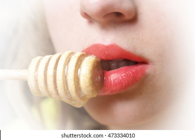 Closeup view on an attractive womans lips while eating honey from a stick.