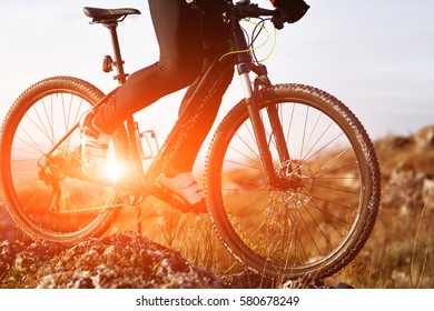 Close-up view on a cyclist. Biker riding a bike on the way view from below on a background of sunrise. - Shutterstock ID 580678249