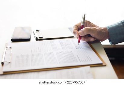 Close-up view on desk office, businessman signing a contract of investment or insurance, legal agreement on the table with pen, white background - Shutterstock ID 2237957307