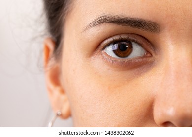 A Closeup View On The Eye Of A Beautiful Young Woman. A Slight Dark Circle Can Be Seen Beneath The Eye. Details Of Girl With Brown Iris. Copy Space On The Left.