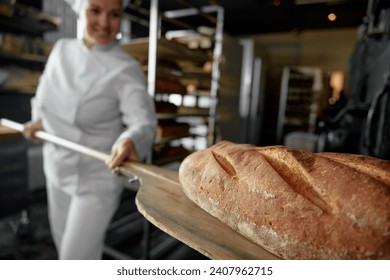 Closeup view on freshly baked artisan bread on shovel in female baker hands - Powered by Shutterstock