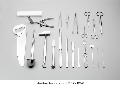 Close-up view on several different medical tools for using in surgery: nippers, knife, scalpel, saw, tweezers, hammer, hook, needle and etc. High quality photo of instruments laid on grey background