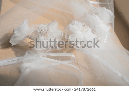 The closeup view on the white bridal headpiece with flower decorations laying on the   the white bridal veil