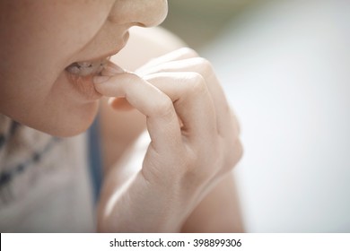 Close-up view on the woman biting nails
