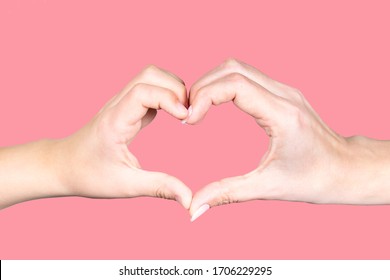 Nahaufnahme einer erwachsenen weiblichen Hand der Mutter und einer kleinen Kinder Hand von Sohn oder Tochter einzeln auf rosafarbenem Hintergrund. Menschen, die Herzgeste zusammen als Symbol oder Zeichen von Liebe und Glück machen.