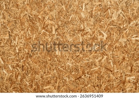 Closeup view of oriented strand board (OSB) surface with chaotic wood chips texture, suitable for construction, design, or background use.