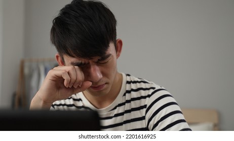 closeup view of an overworked Korean young man having sudden blurry vision is rubbing his eyes while working from home on the computer. - Shutterstock ID 2201616925