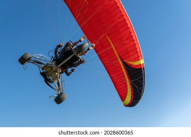 Close-up view of a paramotor vehicle flying over a clear blue sky, view from below. Concept of powered paraglider.
