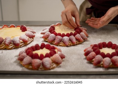 Close-up view of pastry chef hands decorating a cake with fresh red fruits. - Powered by Shutterstock