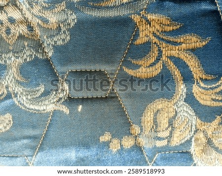 a close-up view of a patterned fabric showcasing a hexagonal design. The fabric features a combination of blue and gold hues, with intricate floral motifs embroidered throughout