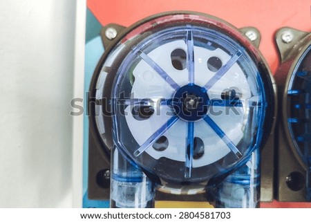 Close-up view of a peristaltic dosing pump with a clear blue plastic housing used for precise liquid chemical dispensing in industrial systems.