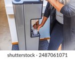 Close-up view of person using water cooler to fill glass with water. Sweden.