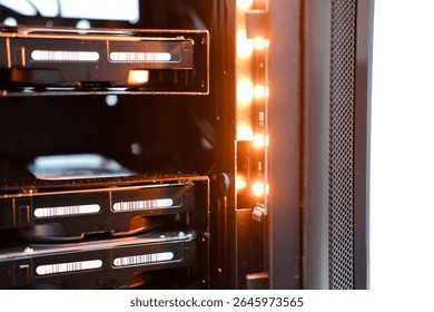 Close-up view of a personal computer server with illuminated components, showcasing hard drive bays and internal lighting, emphasizing technology and data storage systems. Copy space