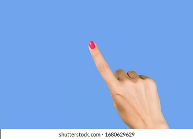 Nahaufnahme einer schönen weiblichen Hand, die Geste mit einem Zeigefinger macht, als ob sie etwas Unsichtbares einzeln auf blauem Hintergrund zeigt oder darauf zeigt.