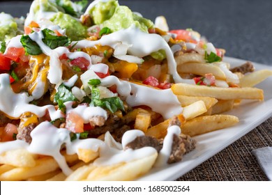 A Closeup View Of A Plate Of Carne Asada Fries, In A Restaurant Or Kitchen Setting.