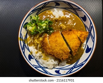 A Closeup View Of A Plate Of Katsu Chicken In A Restaurant Or Kitchen Setting, Dark Background