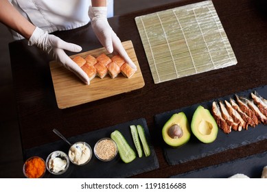 Closeup view of process of preparing rolling sushi. Master is serving fresh delicious rolls on the wooden board - Powered by Shutterstock