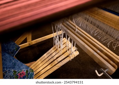 Closeup view of a process weaving loom displaying wooden components and threads, emphasizing traditional craftsmanship and textile artistry in Thai ethnic - Powered by Shutterstock