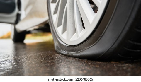 Close-up View Of Punctured, Flat Tire On Rear Wheel Of Automobile. Fault, Damage Wheel While Driving On Asphalt Road. Bad Luck, Accident Concept.