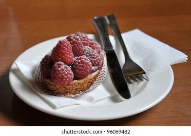 Closeup view of a raspberry cake on white plate.