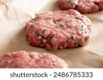 A closeup view of raw ground beef patties on butcher paper.