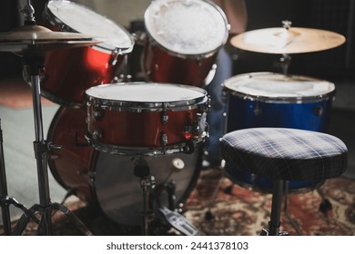 Close-Up View of a Red Acoustic Drum Set With Cymbals and Stool in a Music Studio - Powered by Shutterstock