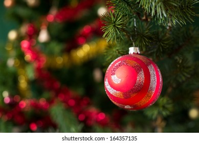 Close-up view of red christmas ball on tree.