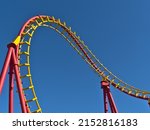 Close-up view of the red and yellow colored rails of a roller coaster in popular amusement park Wurstelprater in Vienna, Austria on sunny day in spring season viewed from public ground.