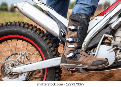Close-up view at rider's motocross boot standing on peg of dirt motorcycle. Safety apparel for riding